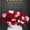 Red and pink rose arrangement in a white vase