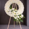 White floral wreath on a wooden easel with a cascading bouquet