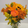 Orange and yellow bouquet in a glass vase with a raffia bow