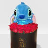 Blue plush toy sitting above a cluster of red roses in a black hat box