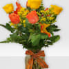 Orange and yellow roses in a glass vase with an orange ribbon