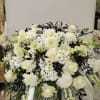White floral funeral spray with roses, daisies, and lilies