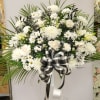 White funeral spray with daisies and chrysanthemums on a stand