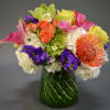 Colorful bouquet with roses, calla lilies, and a protea in a glass vase