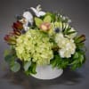 White and pale green floral arrangement in a white container