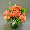 Orange roses and calla lilies in a green glass vase