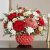 Red roses and white daisies in a red patterned vase with gold ornaments