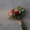 Hand-tied bouquet with red roses and a pink protea