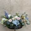 Pastel floral arrangement with blue hydrangeas, pink roses, and white calla lilies in a low vase