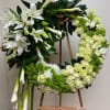Floral wreath with white lilies, cream roses, and green pom-pom blooms