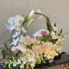 Large floral basket with white orchids, tulips, and pale roses