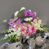 Large floral arrangement with pink, purple, and white blooms in a decorative container