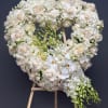 Heart-shaped white floral wreath on a wooden easel