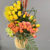 Mixed bouquet of yellow and peach flowers in a striped vase
