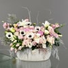 Large pastel flower arrangement in a white ceramic container