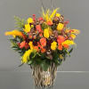 Bouquet of yellow and coral roses with orchids in a decorative vase