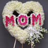 Heart-shaped floral tribute with white hydrangeas, pink roses, and white orchids on an easel