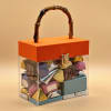 Clear gift box with assorted chocolates and an orange lid with handle