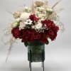 Red and white rose arrangement in a green vase on a stand