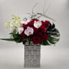 Red roses and white orchids in a tall geometric vase