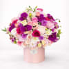 Large bouquet of pink, white, and purple flowers in a pink hat box