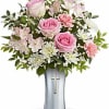 Pink roses and white flowers arranged in a silver vase with a cross