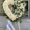 Heart-shaped floral wreath of white roses and lilies on an easel