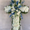 White floral cross arrangement with blue accents on an easel