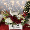 Holiday floral arrangement with red roses and a white deer figurine in a wooden box