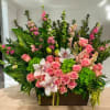 Large floral arrangement with pink roses, white orchids, and green blooms in a rectangular container
