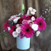 Pink gerbera daisies and roses arranged in a white vase