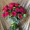 Hot pink roses in a glass vase with green berries and foliage