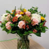 Pink roses and mixed flowers arranged in a glass vase
