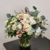 Bouquet of white hydrangeas and peach roses in a glass vase