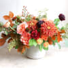 A radiant autumn arrangement in orange hues, burgundy, and spray roses with