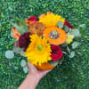 Handheld bouquet with sunflowers, red roses, and an orange pumpkin accent