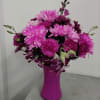 Pink and purple mixed flower arrangement in a bright pink vase