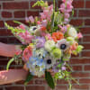 Handheld bouquet of pastel pink, white, blue, and peach flowers