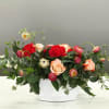 Mixed bouquet of roses and red carnations in a white container