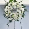Standing white wreath complete with daisies, carnations, and roses to honor the