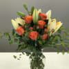 Orange roses and cream lilies in a glass vase