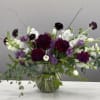 Purple and white floral arrangement in a glass vase