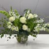 White roses and snapdragons in a glass vase with green hydrangea