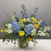 Blue hydrangeas with yellow and white flowers in a glass vase