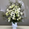 White lilies and roses arranged in a white vase