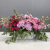 Pink floral arrangement in a rectangular white vase