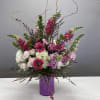 Pink and white floral arrangement in a purple vase