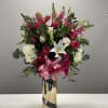 Tall bouquet of pink roses and white lilies in a gold vase with a pink ribbon