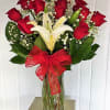Bouquet of red roses and white lilies in a glass vase with a red bow