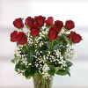 Red roses arranged in a clear glass vase with white filler flowers.